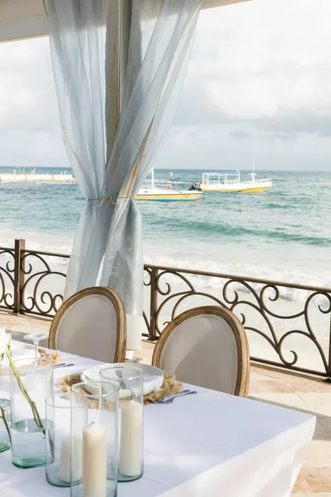 Romantic reception table set by the ocean with candlelight and flowing drapes at Villa La Joya.