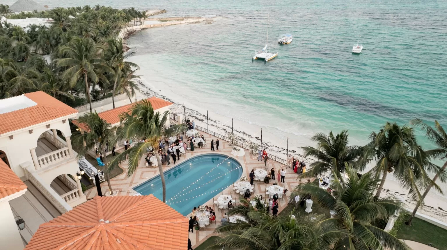 Poolside wedding celebration at Villa La Joya with guests dining and dancing by the turquoise Caribbean Sea.