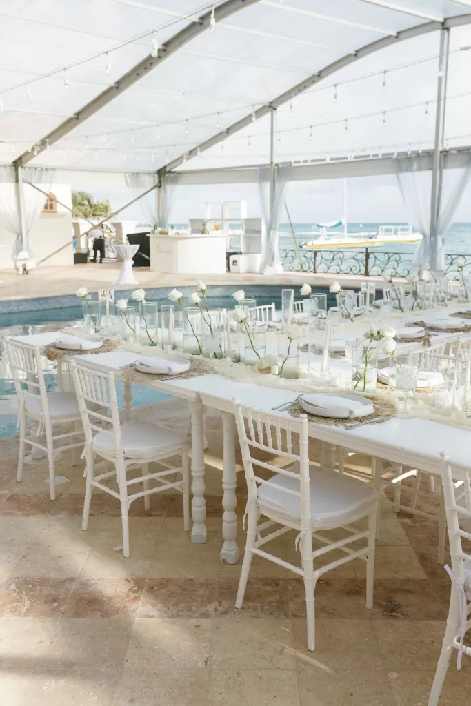Coastal wedding reception setup with white chairs and minimalist white roses at Villa La Joya.