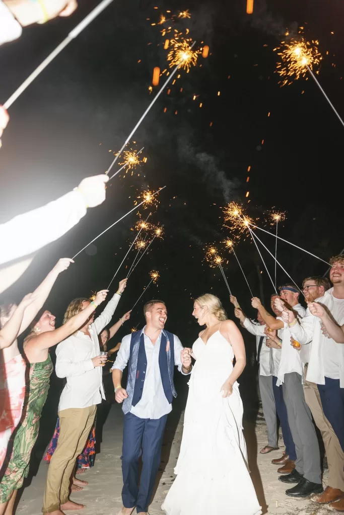 Joyful sparkler exit on the beach with bride and groom surrounded by cheering guests at Villa La Joya.