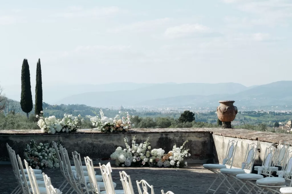 Elegant ceremony setup with white floral arrangements overlooking the Tuscan hills at Villa Medicea di Lilliano.