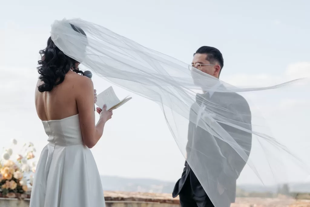Bride reading vows with her veil floating in the wind during a romantic ceremony at Villa Medicea di Lilliano.