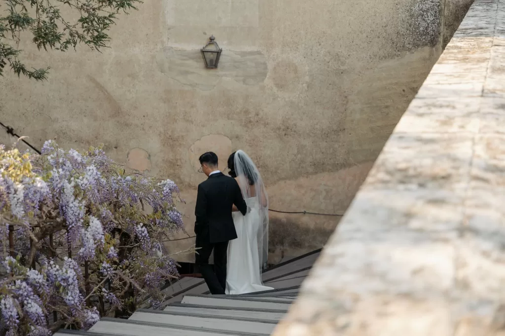Bride and groom walking hand in hand on the stone terrace of Villa di Maiano.