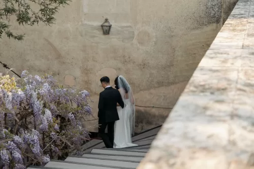 Bride and groom walking hand in hand on the stone terrace of Villa di Maiano.