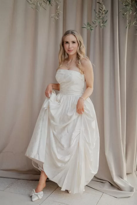 The bride poses gracefully in a strapless silk gown under soft draping at Cigarral de las Mercedes.
