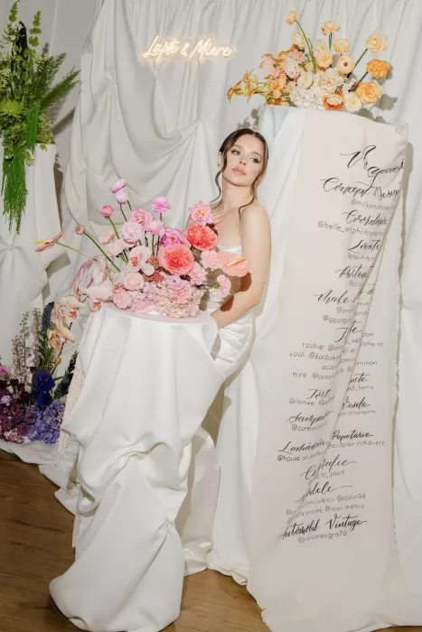 Full-length shot of a bride next to an elegant floral display with modern calligraphy decor.