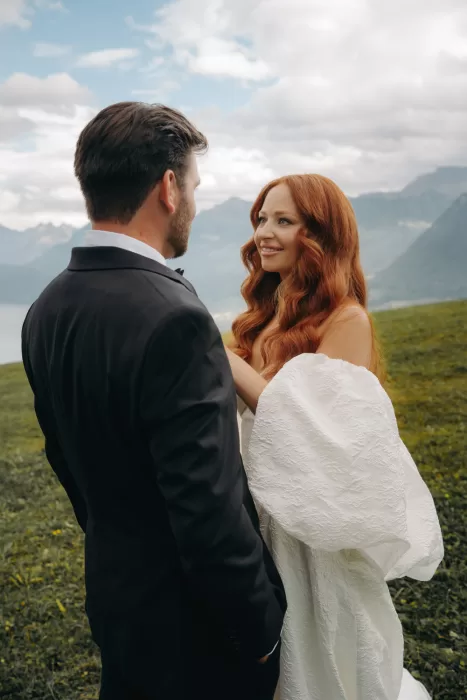 Bride and groom smile at each other with mountains behind them, sharing a quiet moment at Hotel Villa Honegg.