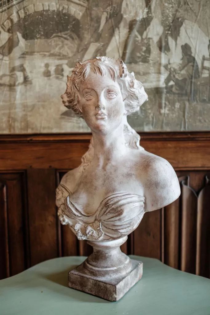 Romantic stone bust of a woman displayed on a mint green table at Château Challain, adding vintage elegance to the space.