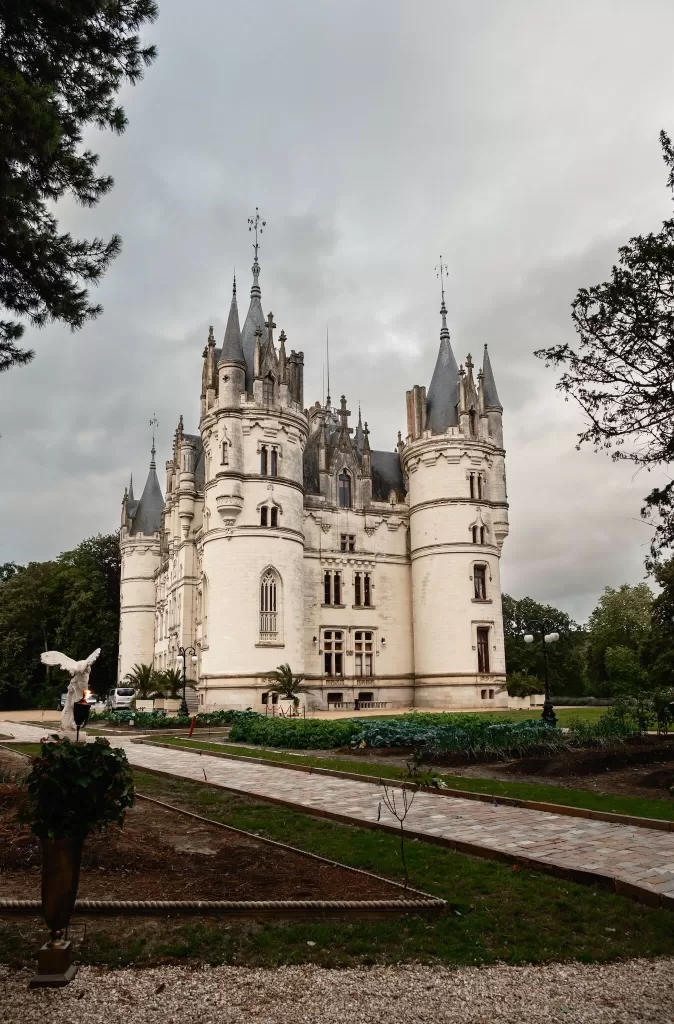 Dramatic view of Chateau Challain’s fairytale castle facade with turrets under moody skies.