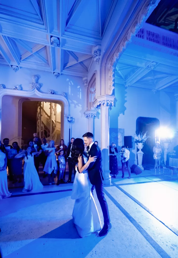 First dance at Chateau Challain beneath the grand ceiling, surrounded by guests and soft blue lighting.