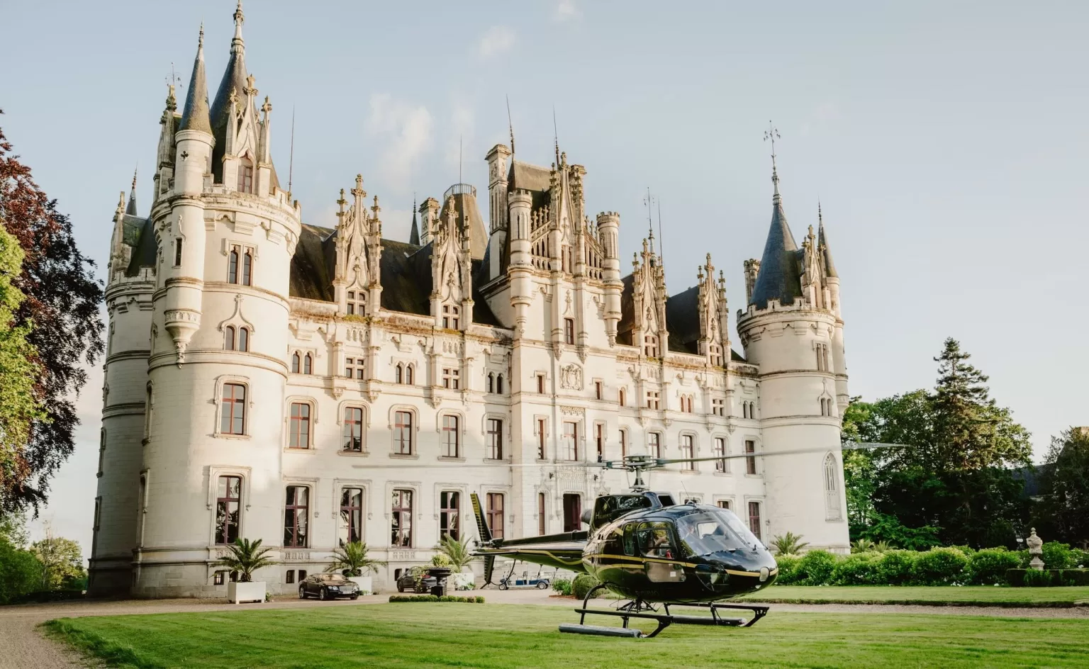 Helicopter parked on the lawn in front of Château Challain’s fairytale castle, offering an ultra-luxury wedding arrival.
