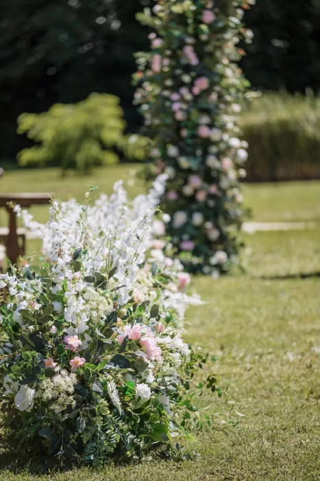 Lush floral aisle arrangement with white and blush flowers on the lawn at Château de la Couronne.