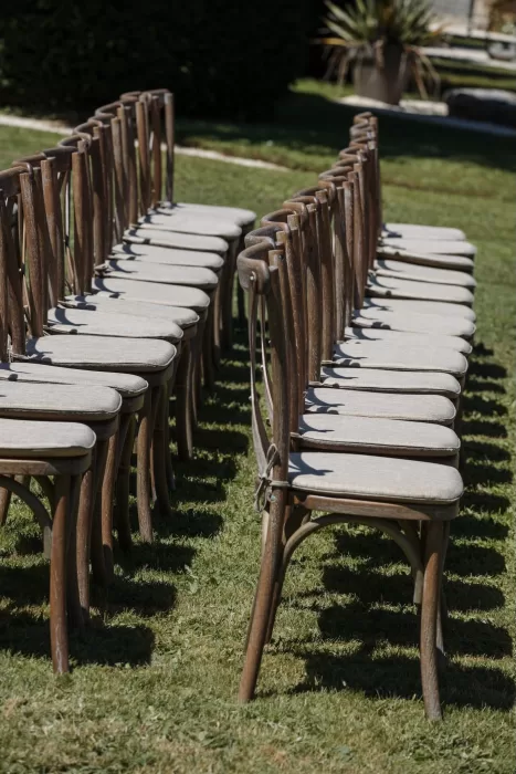 Neatly arranged wooden chairs with linen cushions for an outdoor wedding at Château de la Couronne.