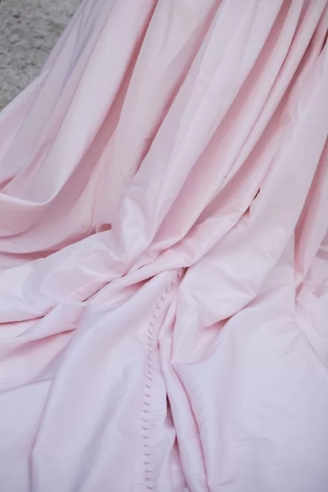 Close-up of soft blush wedding gown with elegant fabric buttons and romantic folds