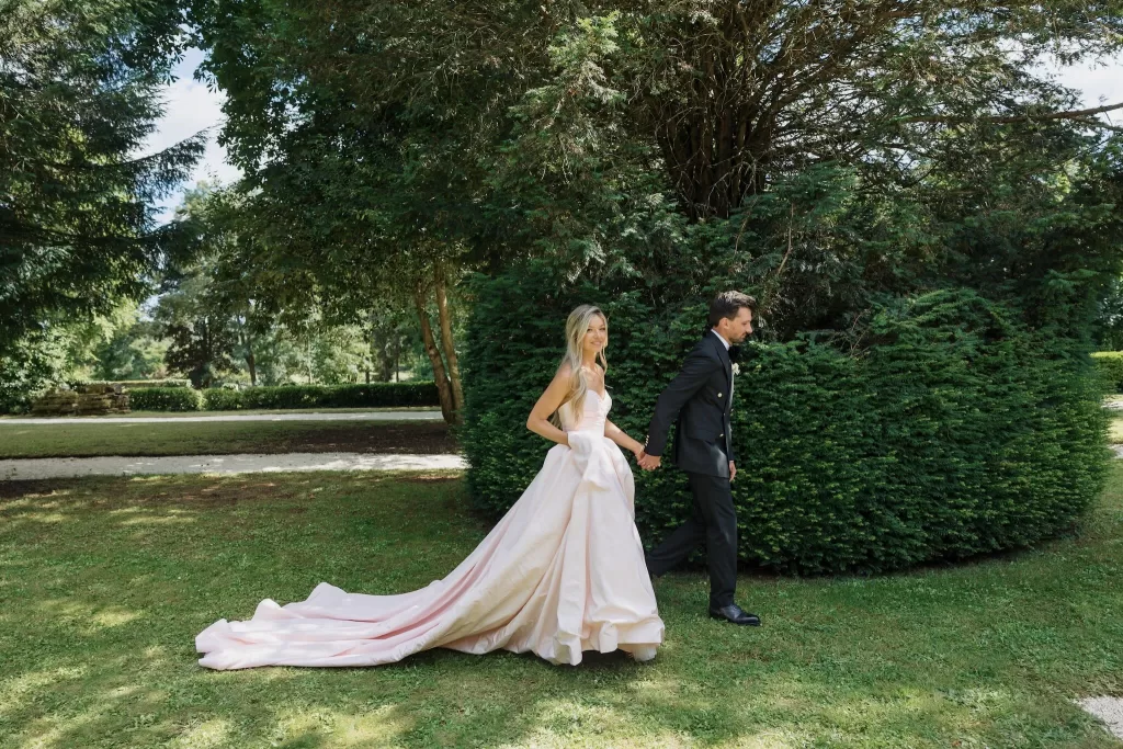 Bride and groom walking hand in hand through the manicured gardens of Château de la Couronne