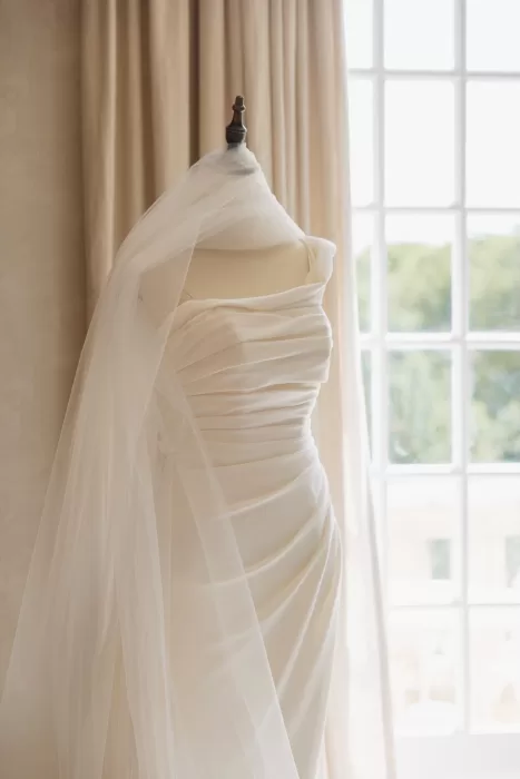 Elegant ruched wedding dress draped with tulle, captured in soft natural light at Château de la Couronne.