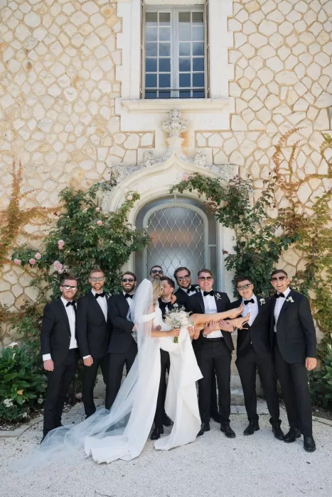 Playful moment with the groom and groomsmen lifting the bride in front of Château de la Couronne