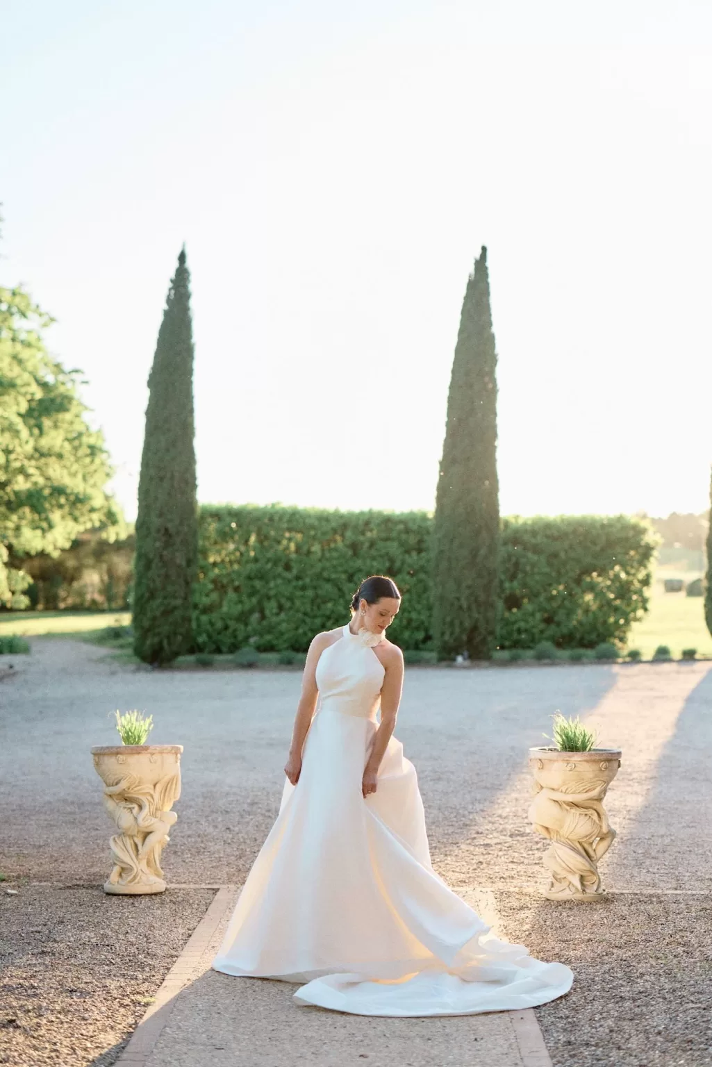 Bride in minimalist halterneck gown at Château de Sanse during golden hour.
