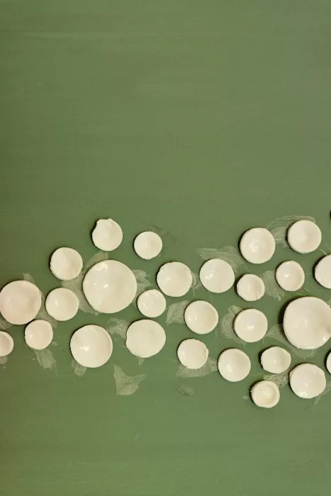 Artistic ceramic wall installation in soft white against green at Chateau de Sanse.