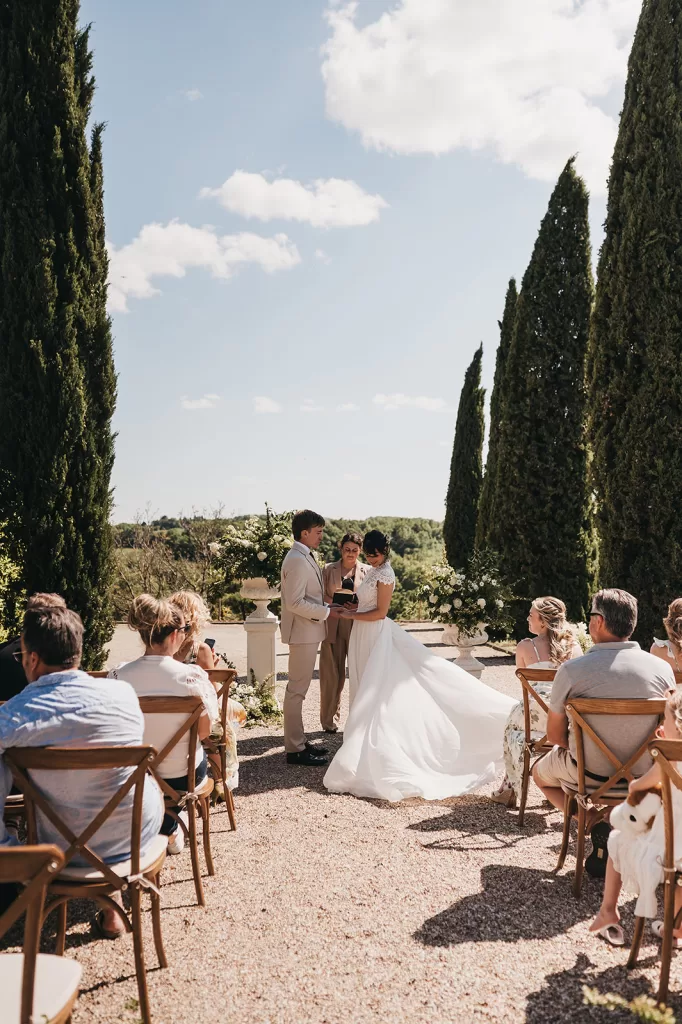 Outdoor wedding ceremony framed by cypress trees with countryside backdrop at Château de Sanse