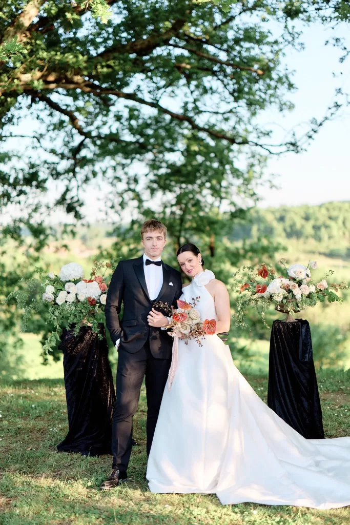 Bride and groom posing in garden floral arch at Chateau de Sanse.
