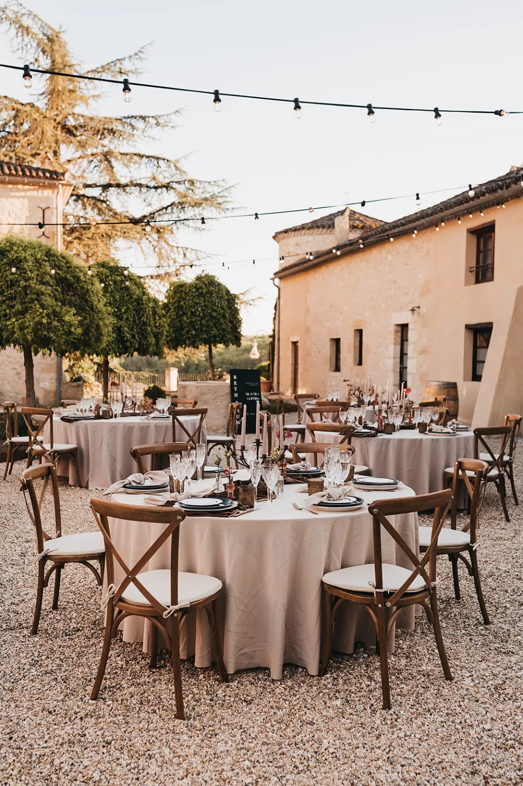 Round table reception setup in the sunlit courtyard at Château de Sanse