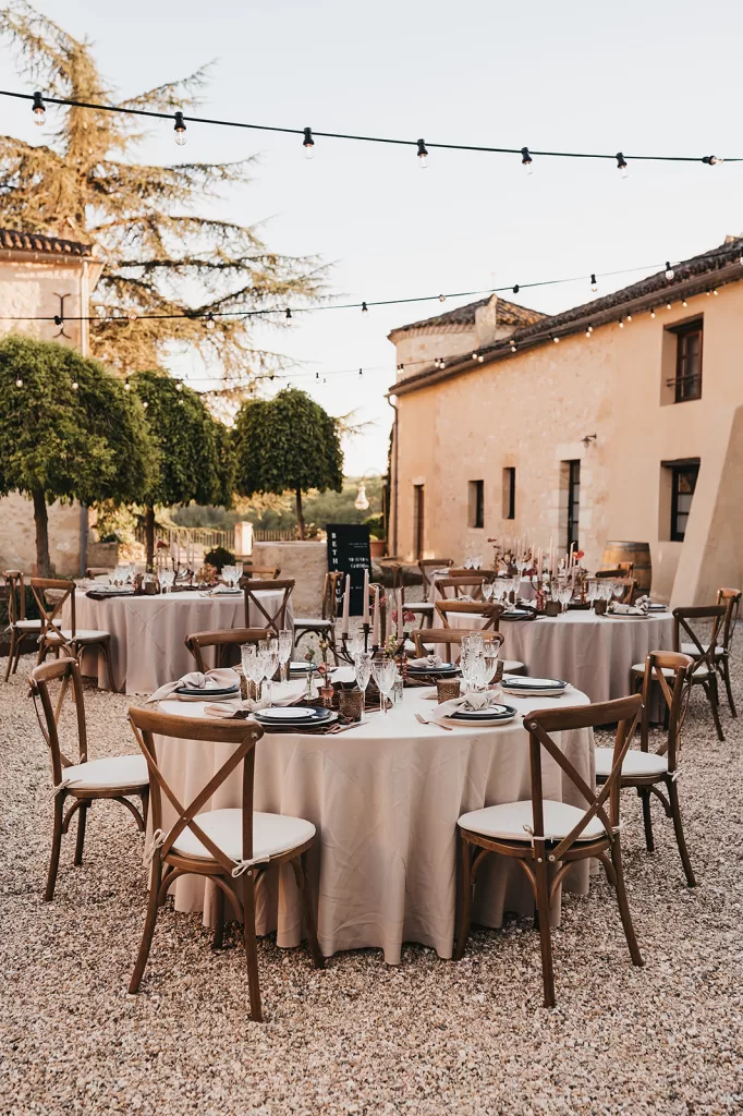 Round table reception setup in the sunlit courtyard at Château de Sanse