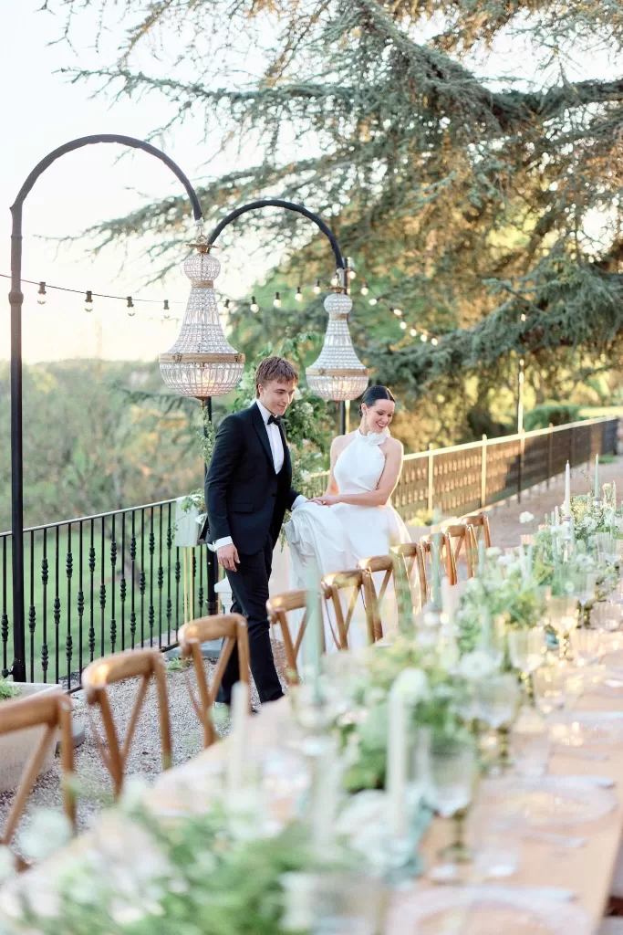 Bride and groom walking along elegant outdoor tablescape at Château de Sanse.