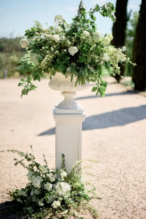 Lush white and green ceremony flowers in a classical urn at Chateau de Sanse.