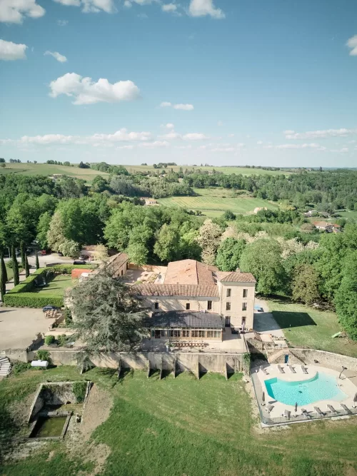 Aerial view of Château de Sanse and surrounding countryside on a clear spring day.
