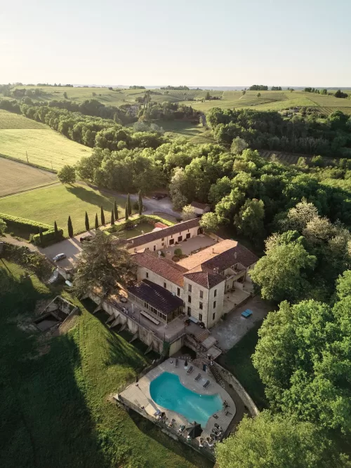 Sunset aerial of Château de Sanse nestled in the rolling French countryside.