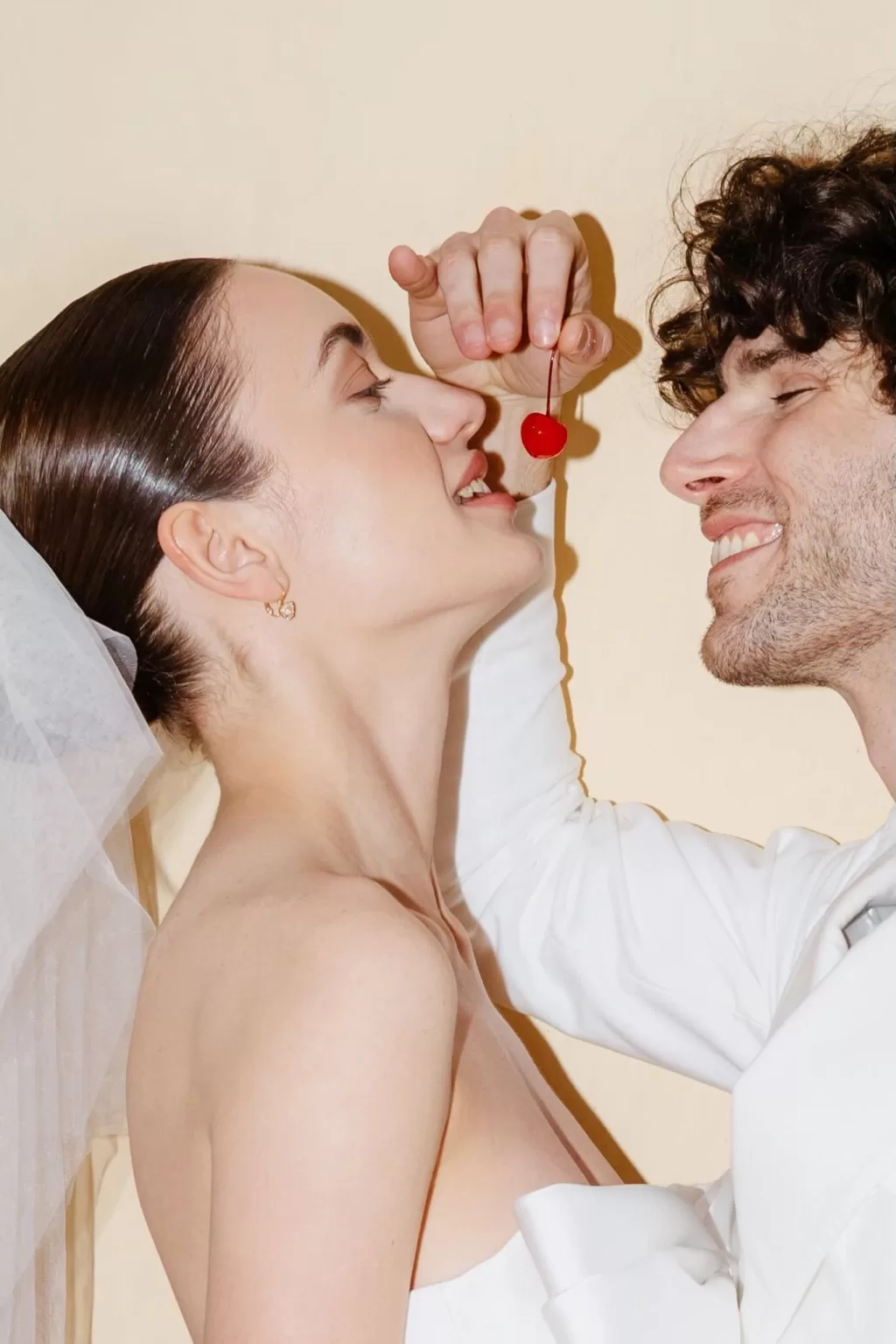 Playful close-up of groom holding a cherry above the bride’s lips, brimming with personality, by The Duo Photography.