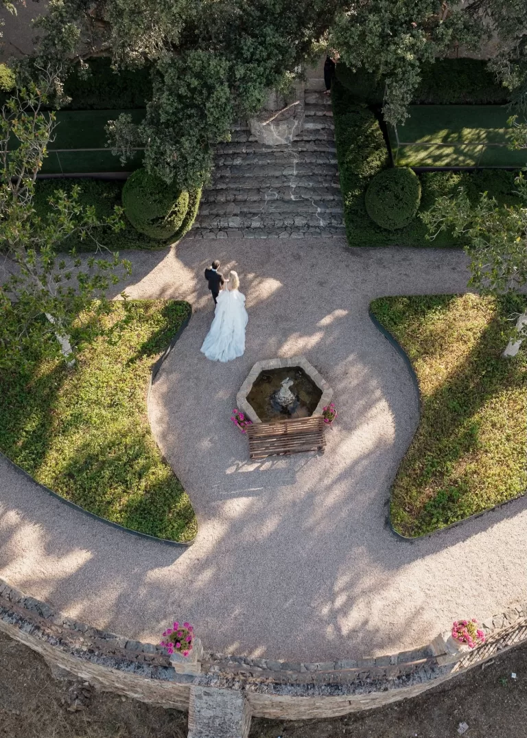 Aerial view of the bride and groom strolling through the manicured gardens of Cigarral de las Mercedes.