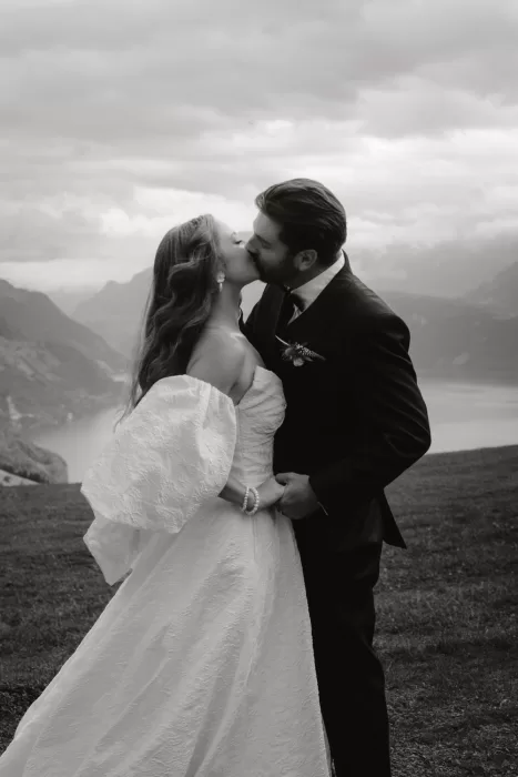 Bride and groom kiss softly with moody skies and lake views behind them at Hotel Villa Honegg.