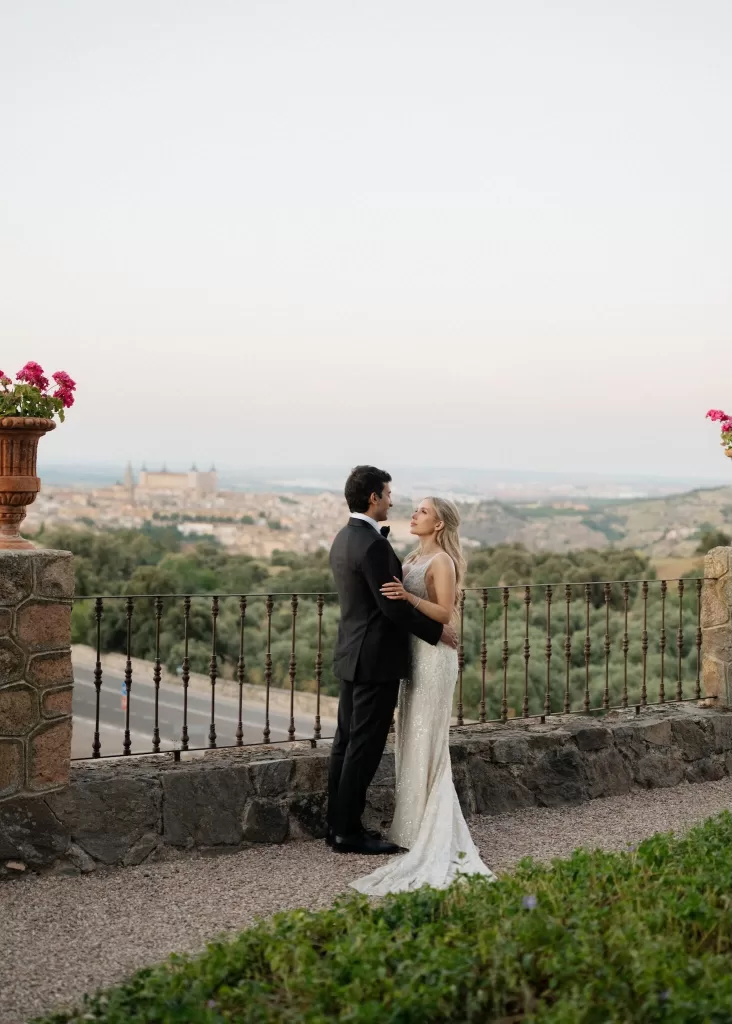 Bride and groom embrace at sunset overlooking Toledo from the terrace at Cigarral de las Mercedes.