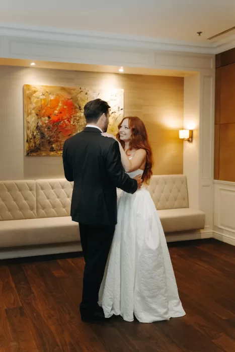 Bride and groom share their first dance in a softly lit indoor reception space at Hotel Villa Honegg, smiling warmly at one another.