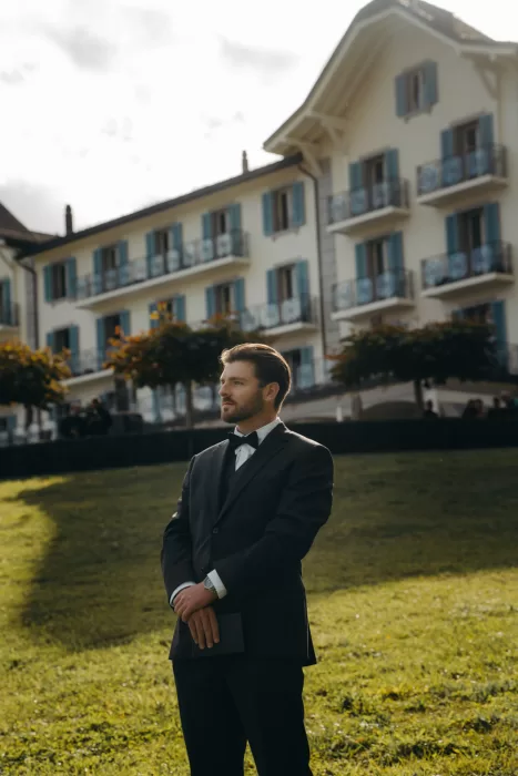 Groom in black suit waits with anticipation on the lawn of Hotel Villa Honegg, ready for the first look.