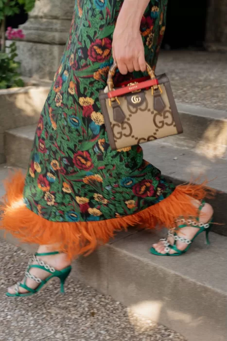 Stylish wedding guest walking down steps in a vibrant floral dress with feather trim at Cigarral de las Mercedes.