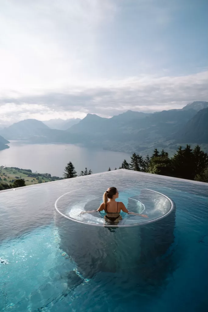 Bride relaxing in the iconic infinity pool at Hotel Villa Honegg, overlooking Lake Lucerne and the Swiss Alps.