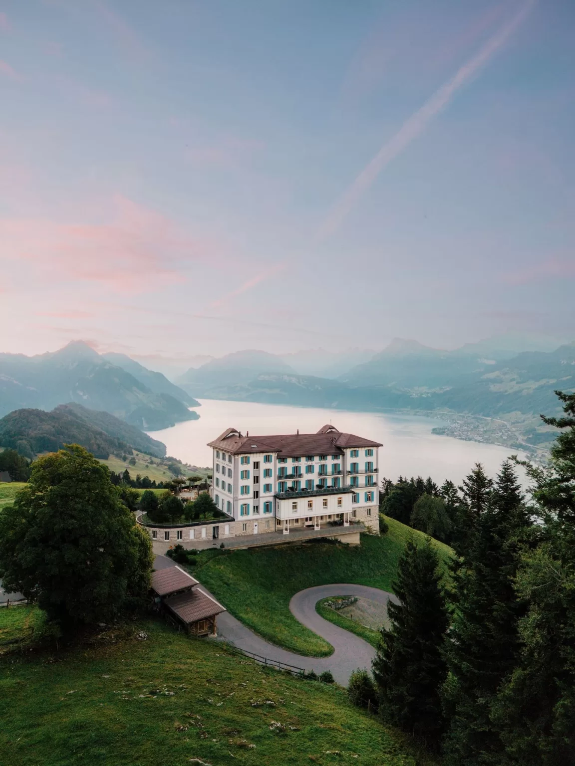 Hotel Villa Honegg at golden hour with sweeping views of Lake Lucerne and pastel skies.