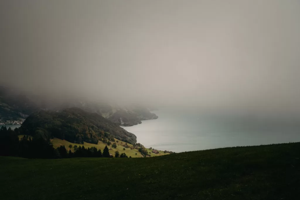 Moody alpine landscape view from Hotel Villa Honegg with mist rolling over Lake Lucerne and forested hills below.