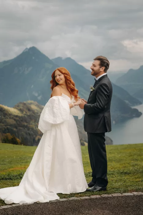 Bride and groom laugh together against a backdrop of Swiss mountains and Lake Lucerne near Hotel Villa Honegg.