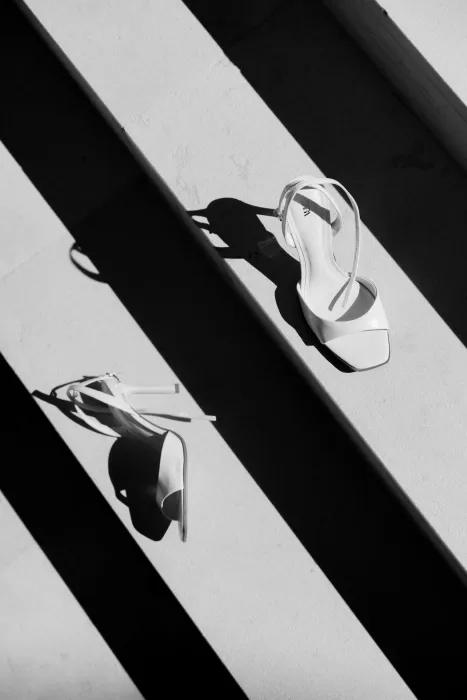 Bride’s white heels on stone stairs, dramatically lit with geometric shadows at Masia Cabellut.