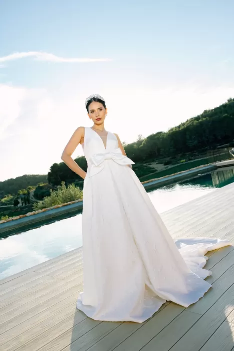 Bride in elegant gown standing confidently by the pool at sunset at Masia Cabellut