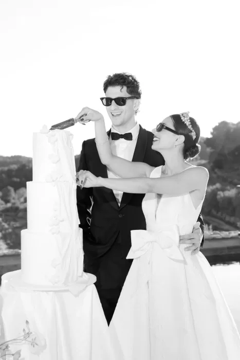 Bride and groom laughing as they cut their wedding cake by the poolside at Masia Cabellut.
