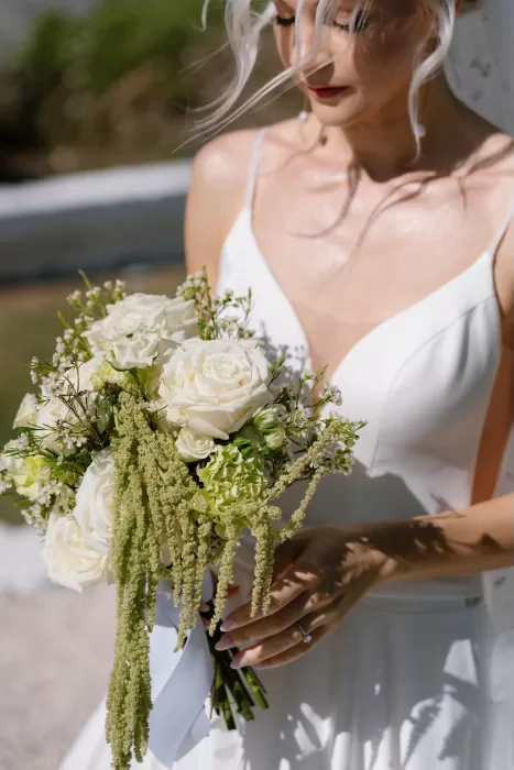 Bride holding a fresh ivory and green bouquet, with soft florals catching the light at Masseria San Giovanni.