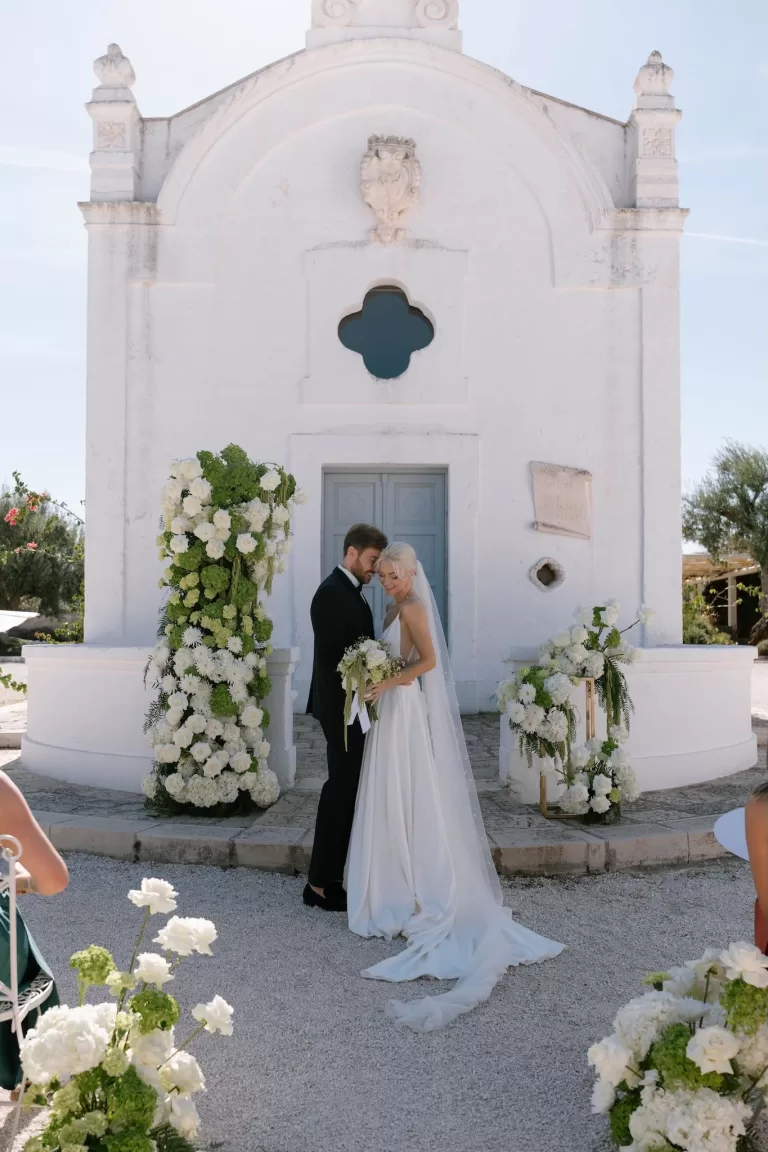 Bride and groom sharing a quiet moment during their vows in front of the chapel at Masseria San Giovanni.