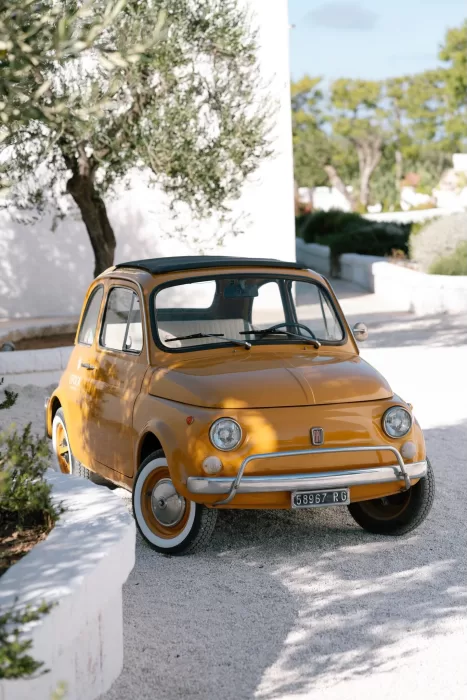 Vintage yellow Fiat parked under olive trees at Masseria San Giovanni, adding a classic Italian touch.