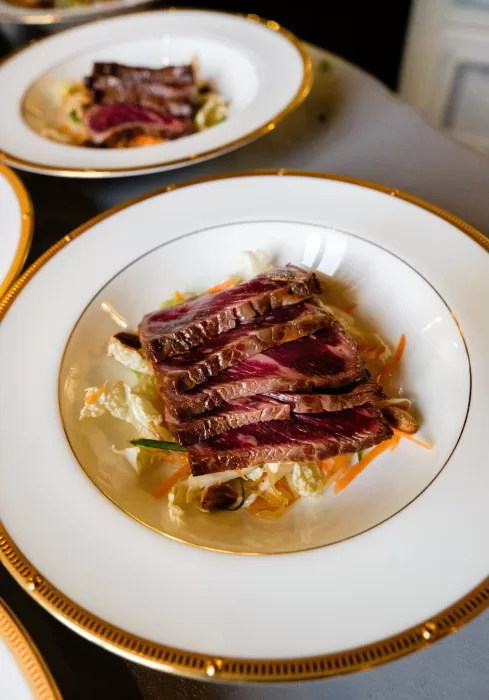 Fine dining plate featuring seared beef slices and fresh vegetables at Château Challain wedding.