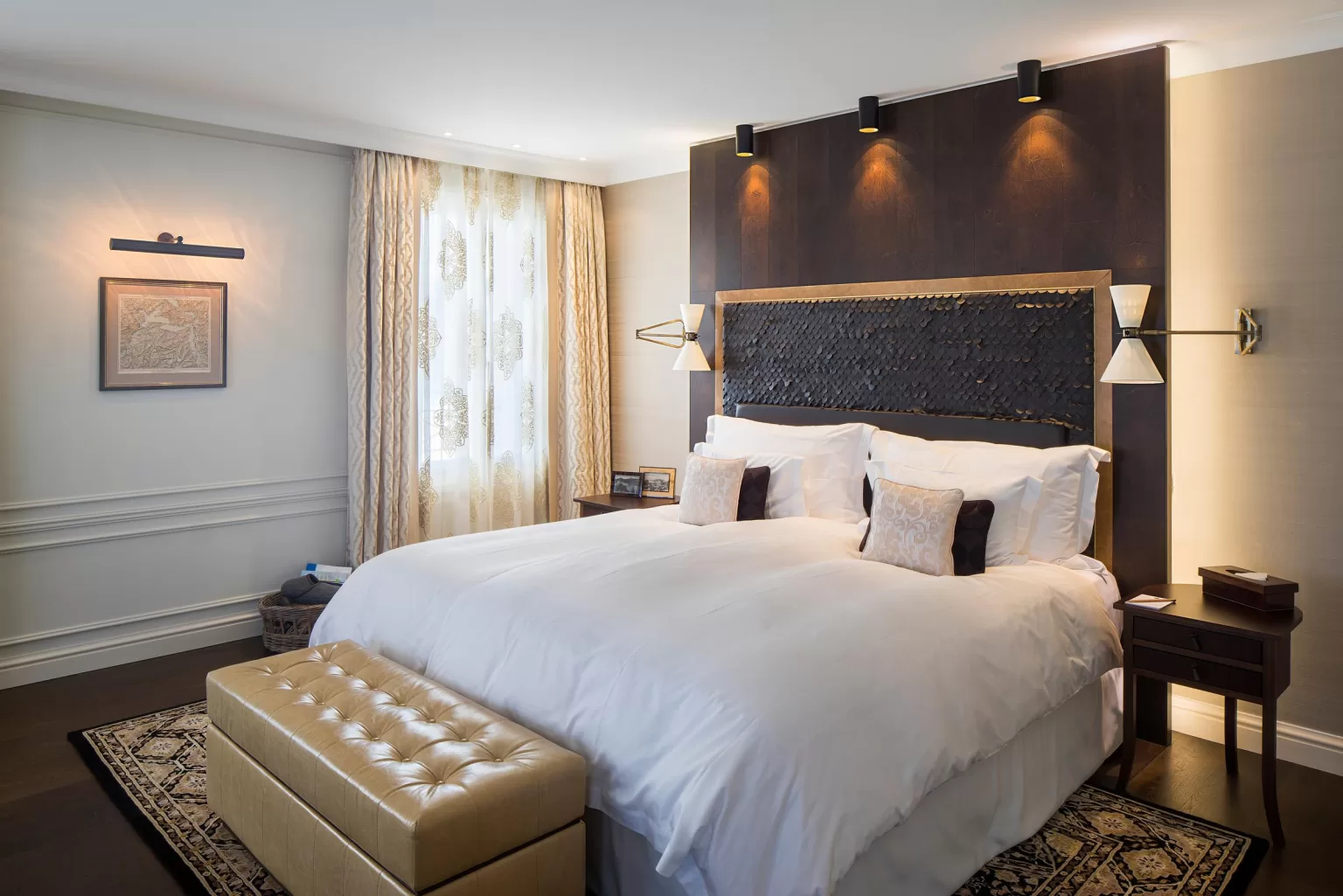 Luxurious master bedroom at Hotel Villa Honegg with warm tones, elegant decor, and mountain light.